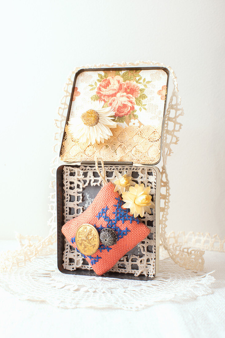 Alte Blechdose dekoriert mit Tapete, Strohblumen, Spitze, Nadelkissen und Knöpfen