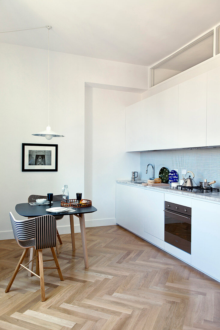 Dining table in small kitchen-dining room with kitchen counter and herringbone parquet floor