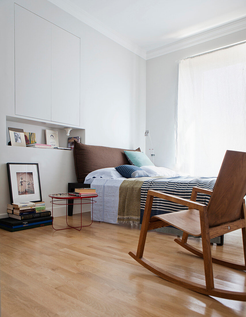 Moderner Schaukelstuhl vorm Bett im Schlafzimmer mit Wandschrank