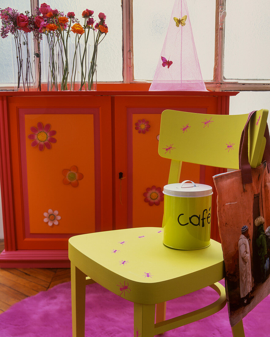 Möbel in knalligen Farben: Neongrüner Stuhl vor rot-oranger Kommode