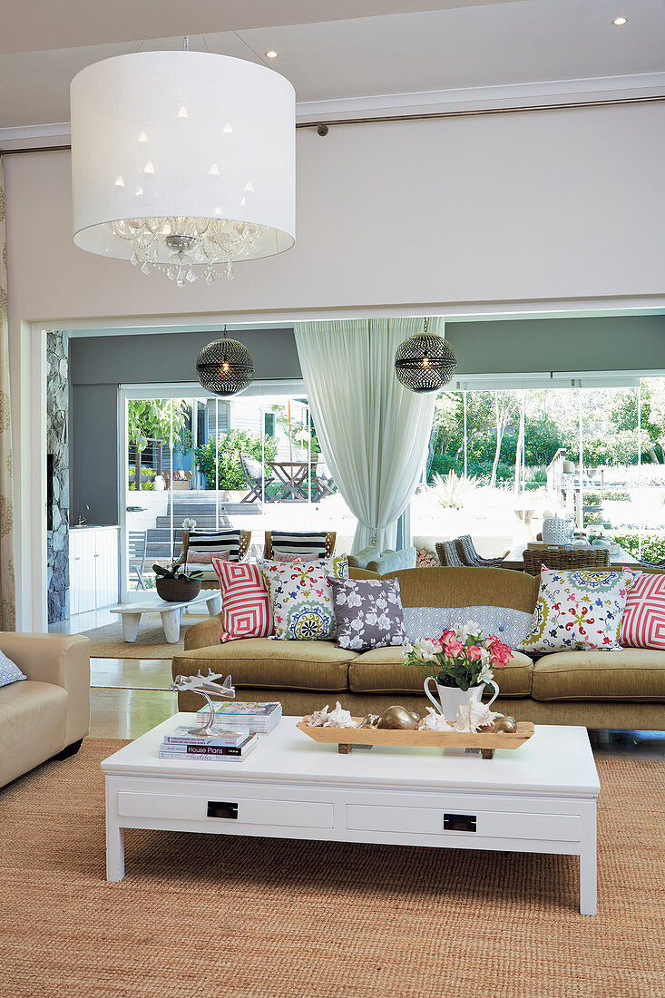 Sofa und Couchtisch auf Sisalteppich in gemütlichem Wohnzimmer mit Fensterfront zum Garten
