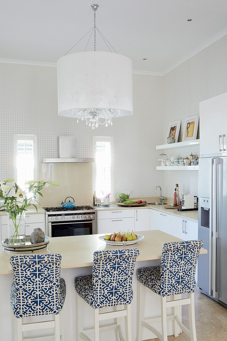 Bar stools with blue-and-white loose covers at breakfast bar in elegant, open-plan kitchen
