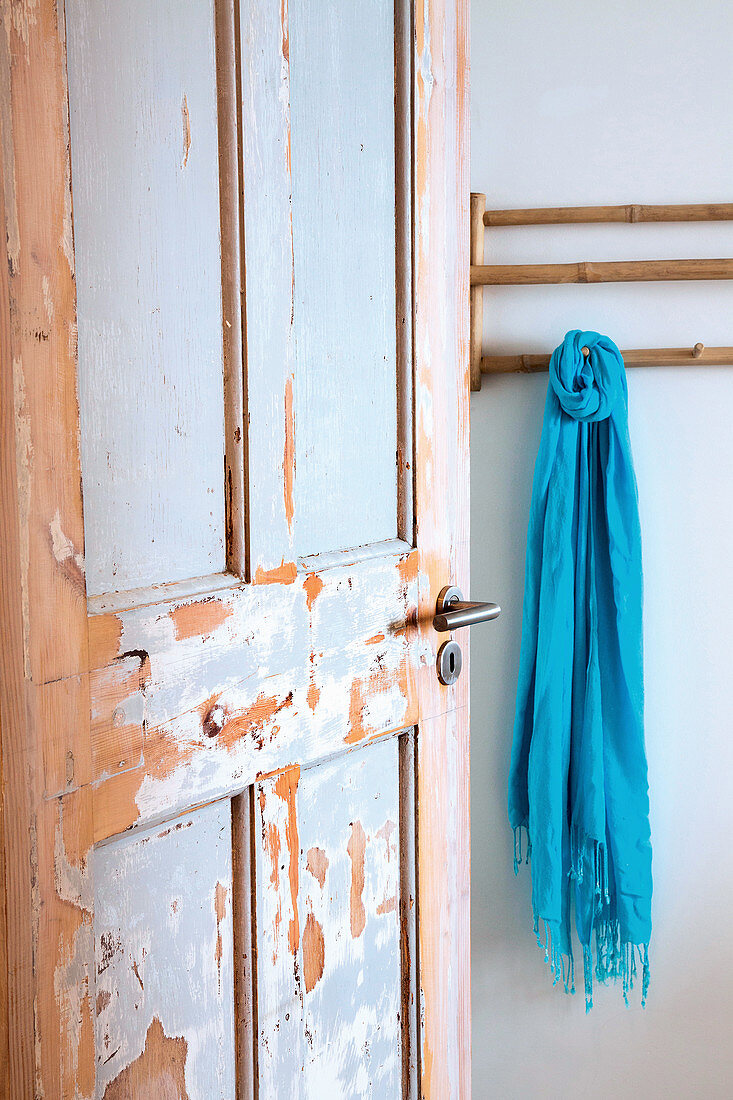 Bamboo coat rack behind shabby-chic wooden door