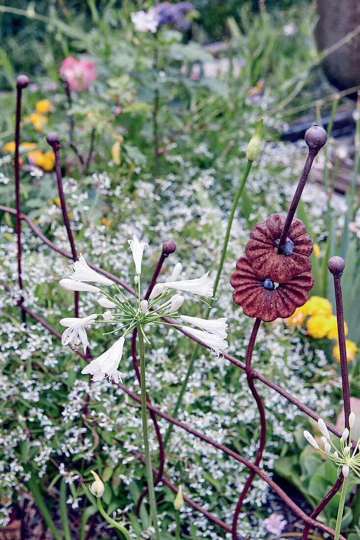 Filigranes rot-braunes Rankgitter im Blumenbeet