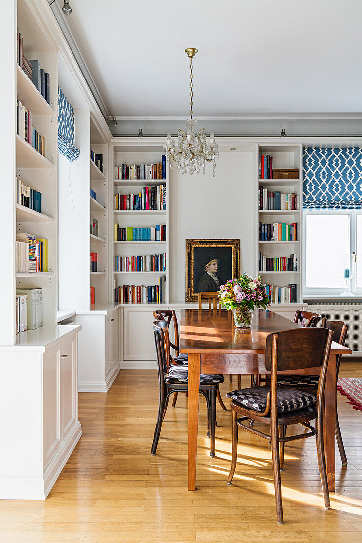 Dining area surrounded by white fitted shelving