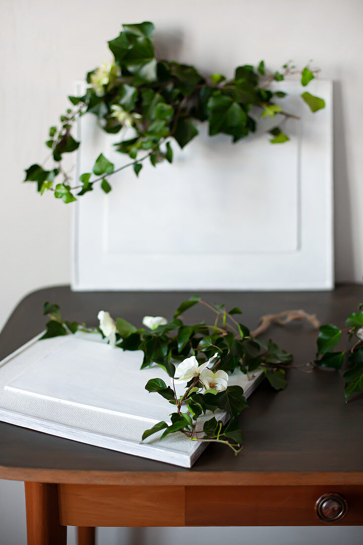 Ivy tendrils on framed pictures painted over in white on old table