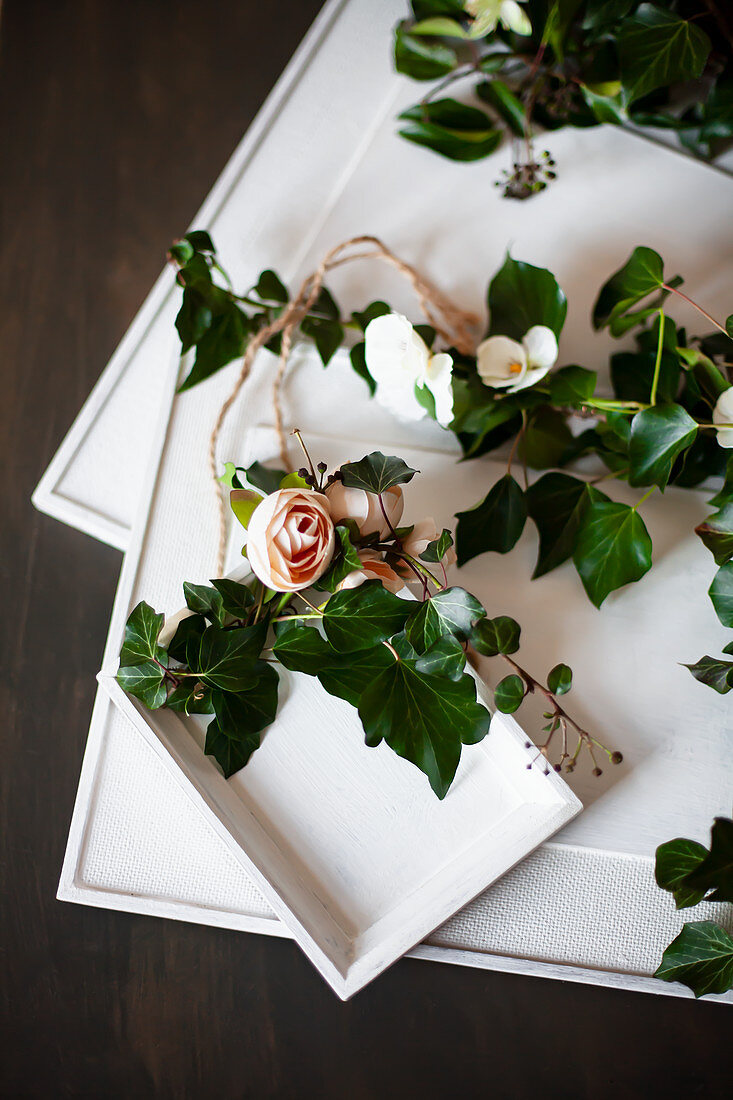 Efeuranken und Stoffblumen um weiß bemalte Bilder