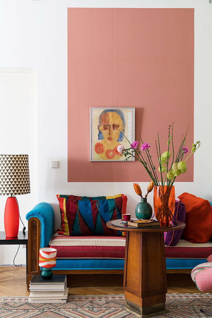 Daybed mit blauen Farbakzenten, Holztisch und rosa Wandfläche im Wohnzimmer
