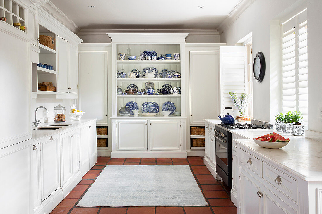 Weiße Küche im Landhausstil mit blau-weißer Geschirrsammlung in Buffetschrank