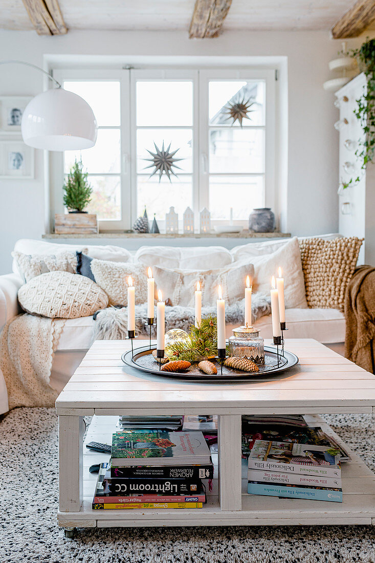 Kranz mit Kerzen auf dem Couchtisch im winterlichen Wohnzimmer