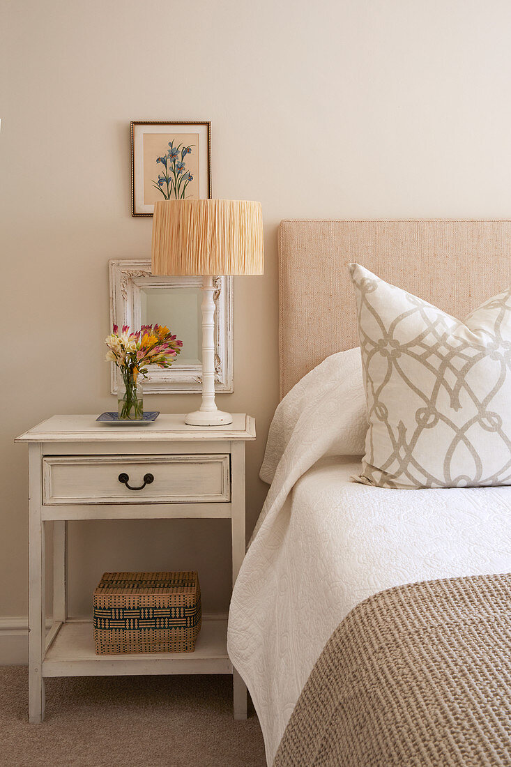 Bed and bedside table in guest bedroom in muted beige and white
