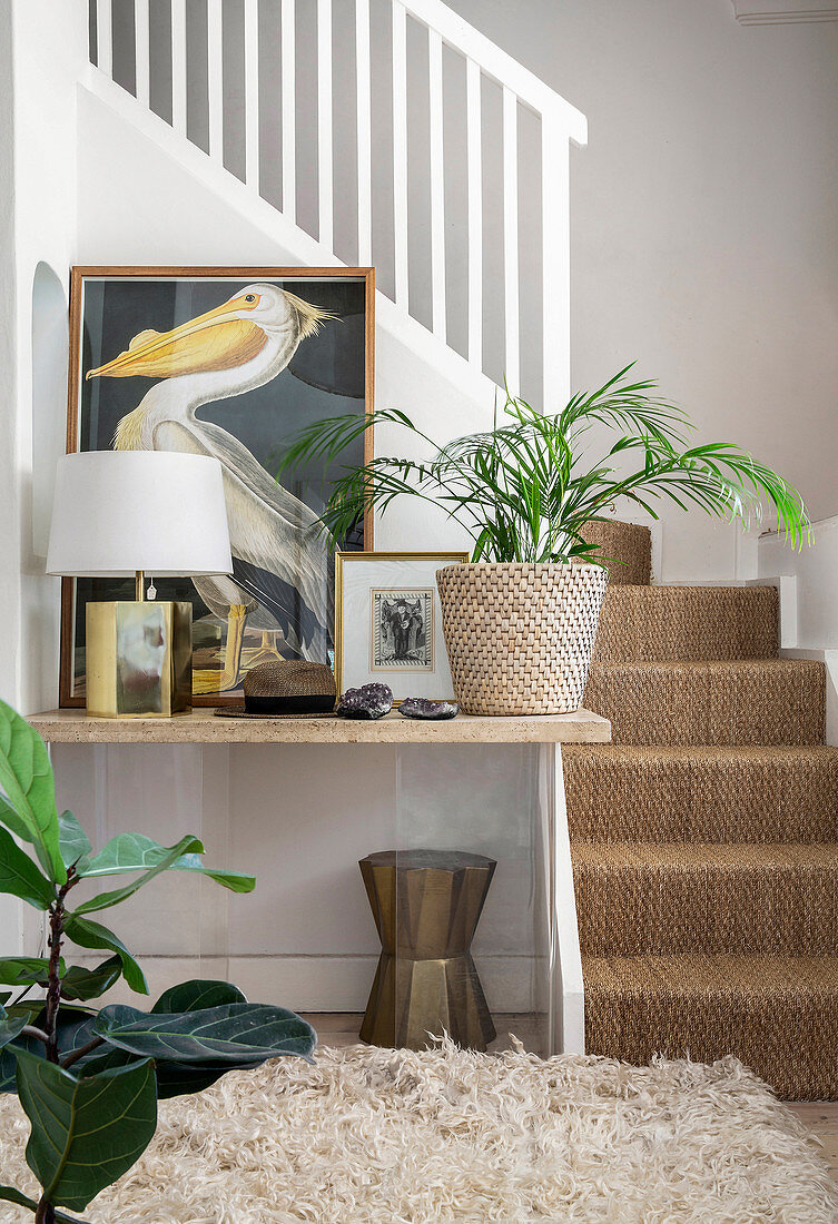 Ablagetisch neben Treppenaufgang dekoriert mit Bildern, Leuchte und Grünpflanze