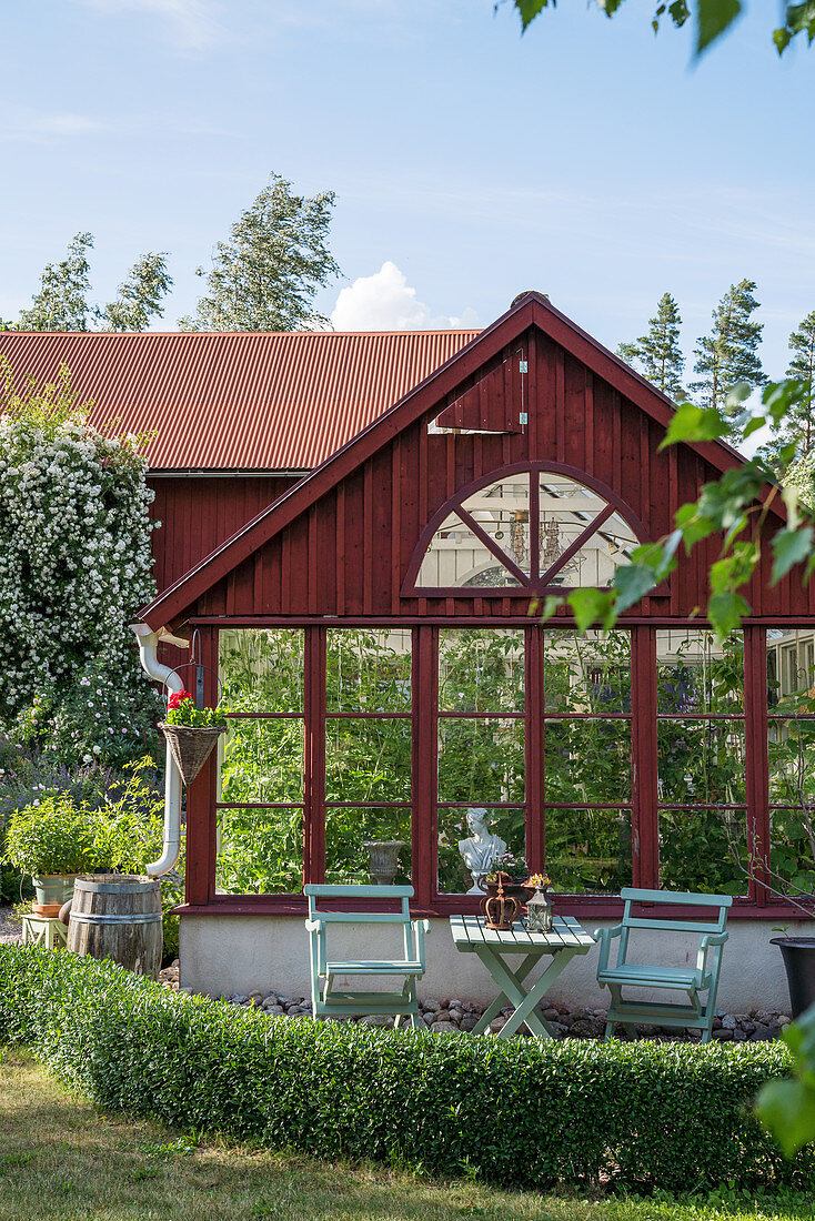 Rotes Gewächshaus im sommerlichen Garten