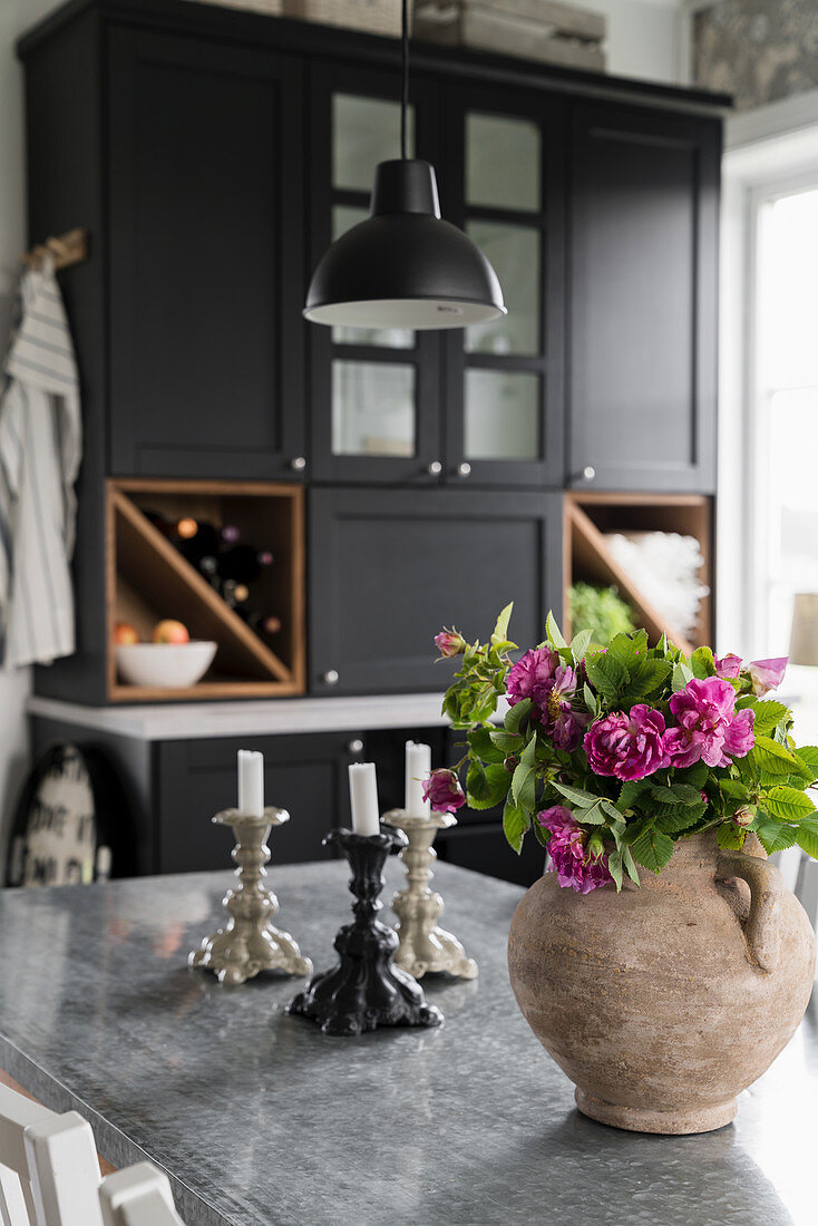 Blumenstrauß in rustikaler Vase auf dem Tisch in einer Landhausküche