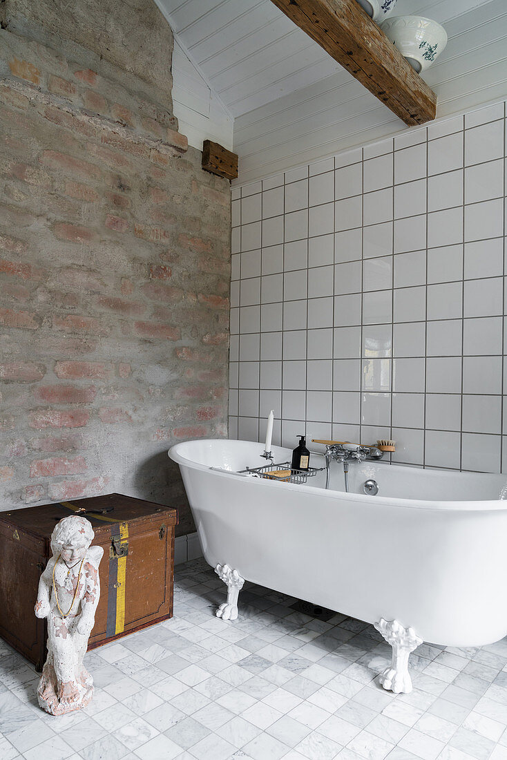 Klassische freistehende Badewanne vor rustikaler Backsteinwand