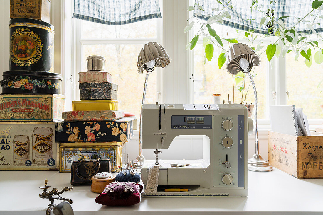 Sewing machines and stack of old tins in front of window