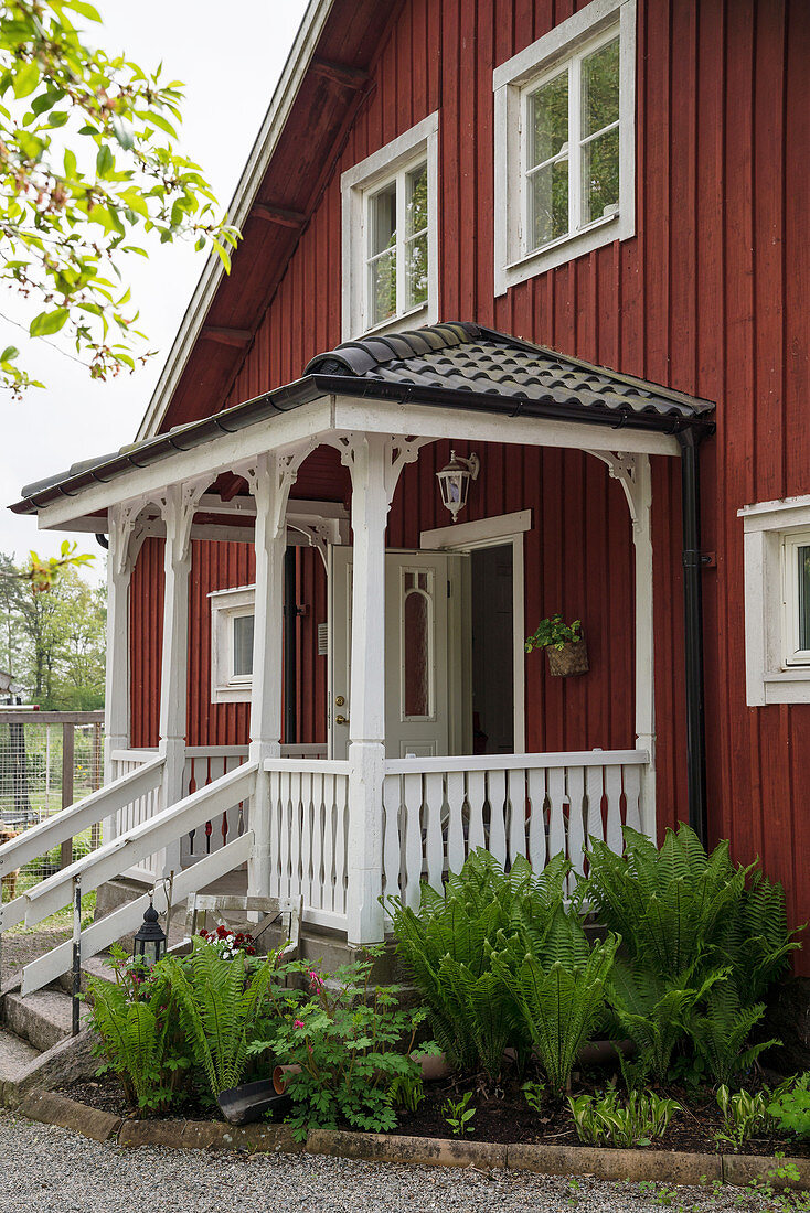Rotes Schwedenhaus mit überdachtem Eingang und Vorgarten