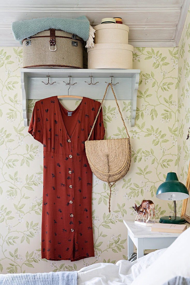 Hat boxes and red dress on wall-mounted coat rack
