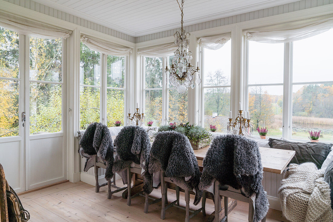 Graue Schaffelle über den Stühlen am Esstisch im Wintergarten
