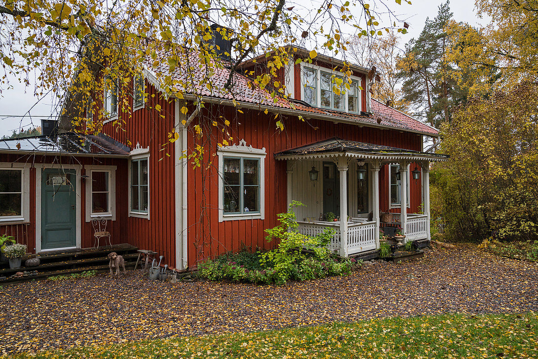Rotes Schwedenhaus mit Vordach im herbstlichen Garten