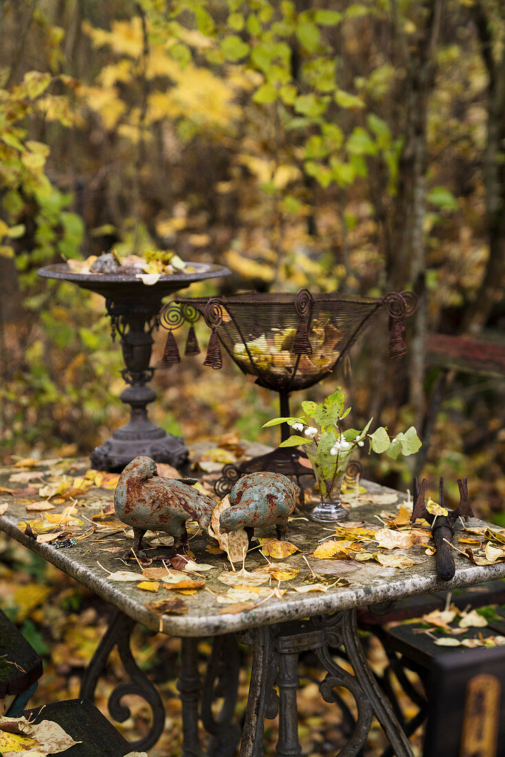 Deko aus rostigem Metall auf einem alten Tisch im herbstlichen Garten