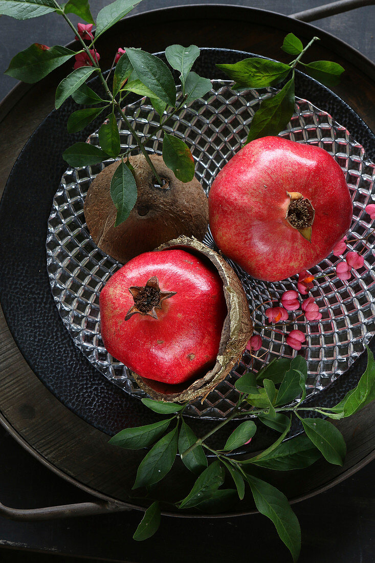Granatäpfel mit Zweigen und Kokosnussschalen als Herbstdekoration