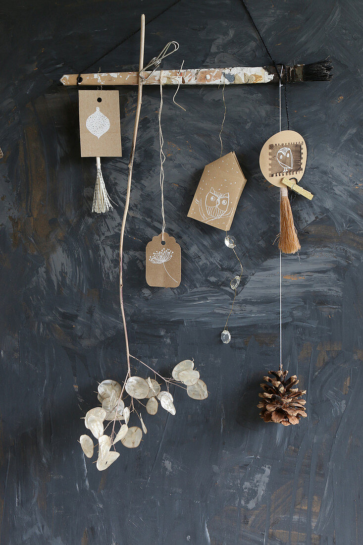 Handmade mobile of tassels, paper pendants, pine cone and sprig of honesty
