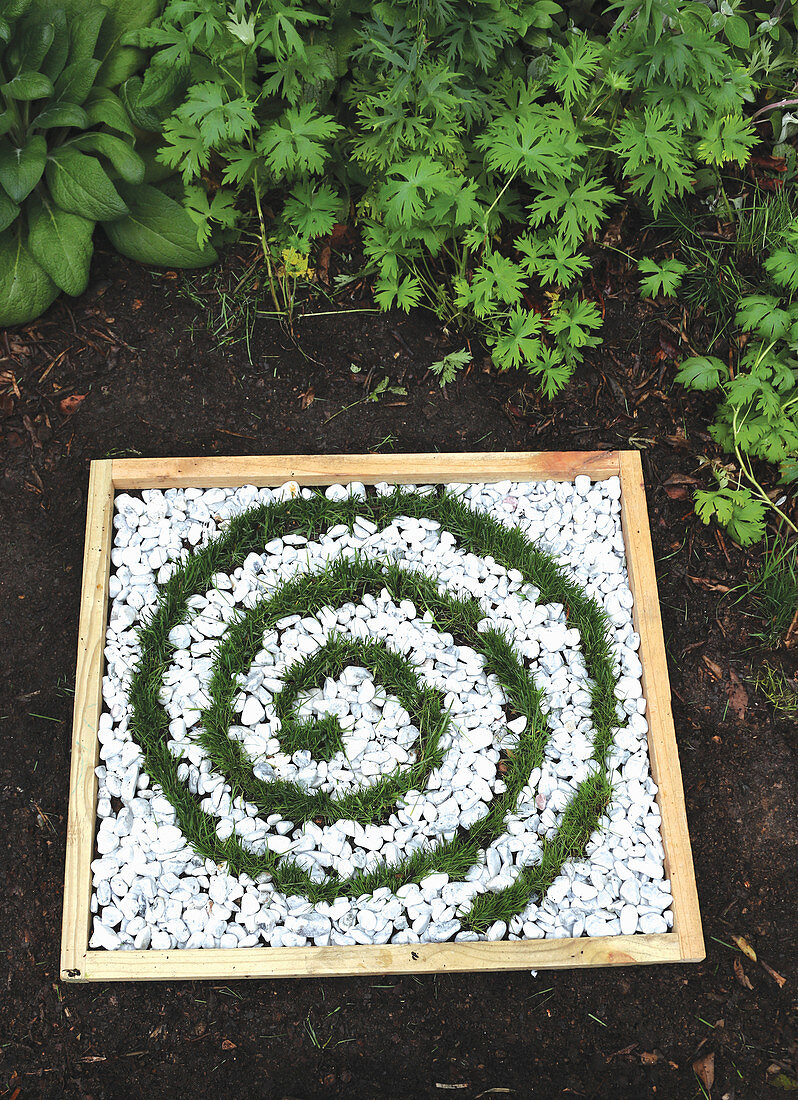 Mini-Beet mit Spirale aus Gras und Kies als Gartendekoration