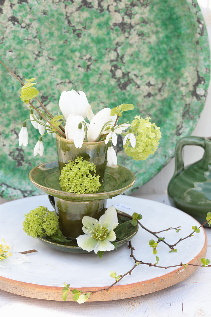 Frühlingshaftes Blütenarrangement in grünen Keramiktassen