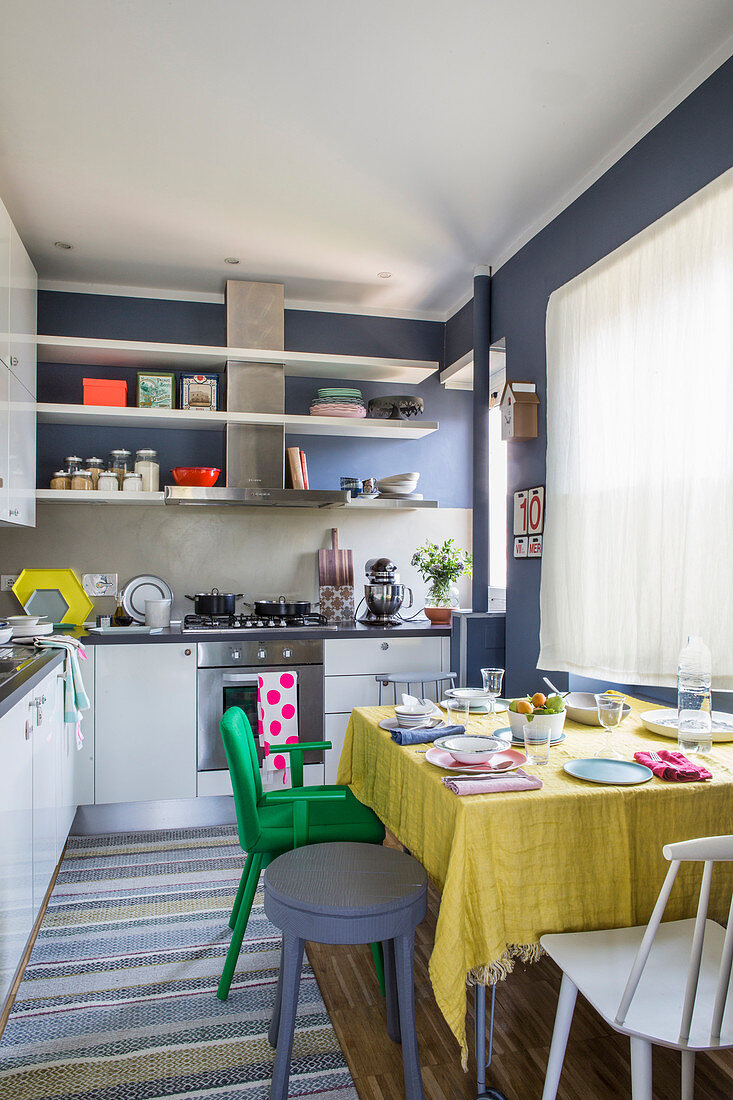 Wohnküche mit weißen Küchenmöbeln und dunkelblauen Wänden