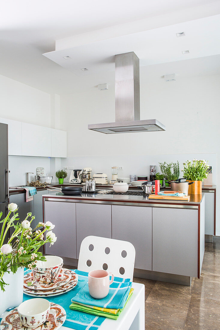 Grey island counter and stainless steel extractor hood in open-plan kitchen
