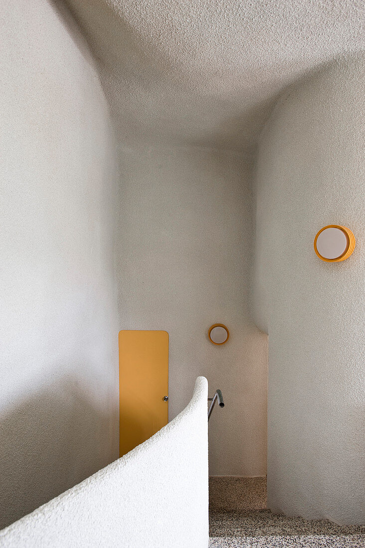 Treppenhaus mit organisch geformten Wänden und gelben Akzenten