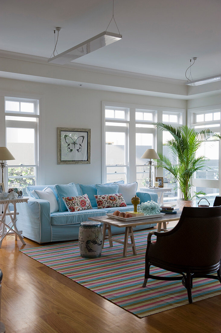 Pale blue sofa in front of large windows in exotic living room