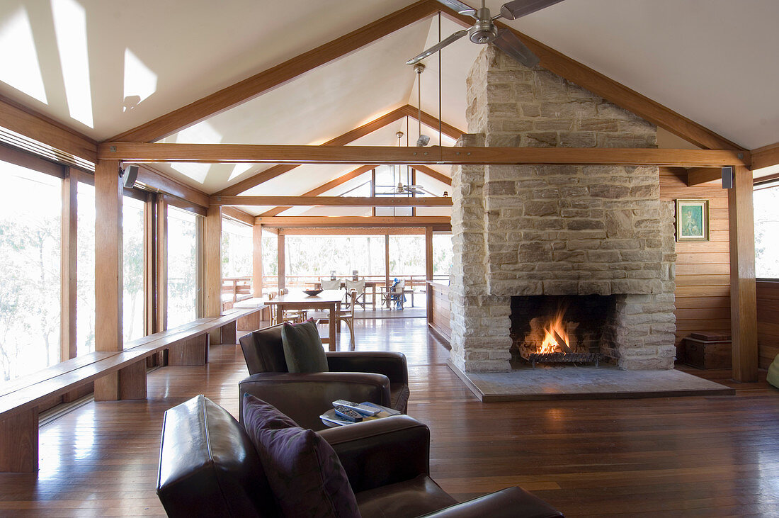 Fireplace under gable ceiling in spacious open-plan interior of modern wooden house