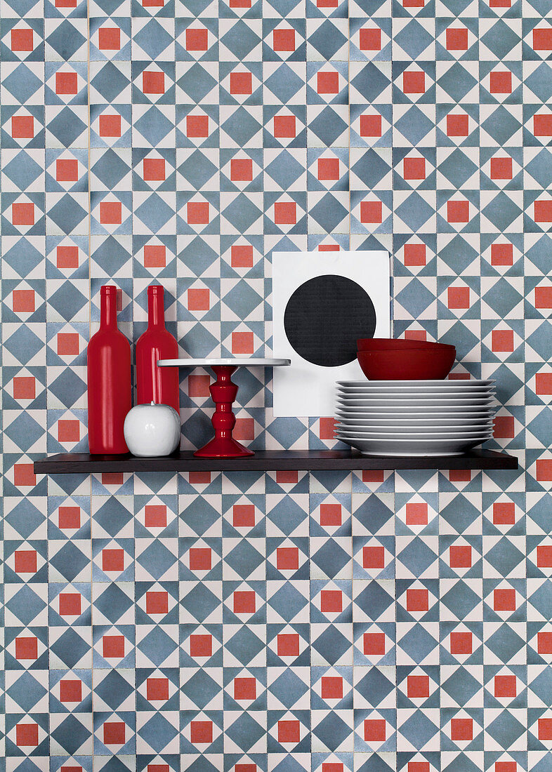 Küchenutensilien auf Regalbrett vor blau-roter Tapete mit grafischem Muster