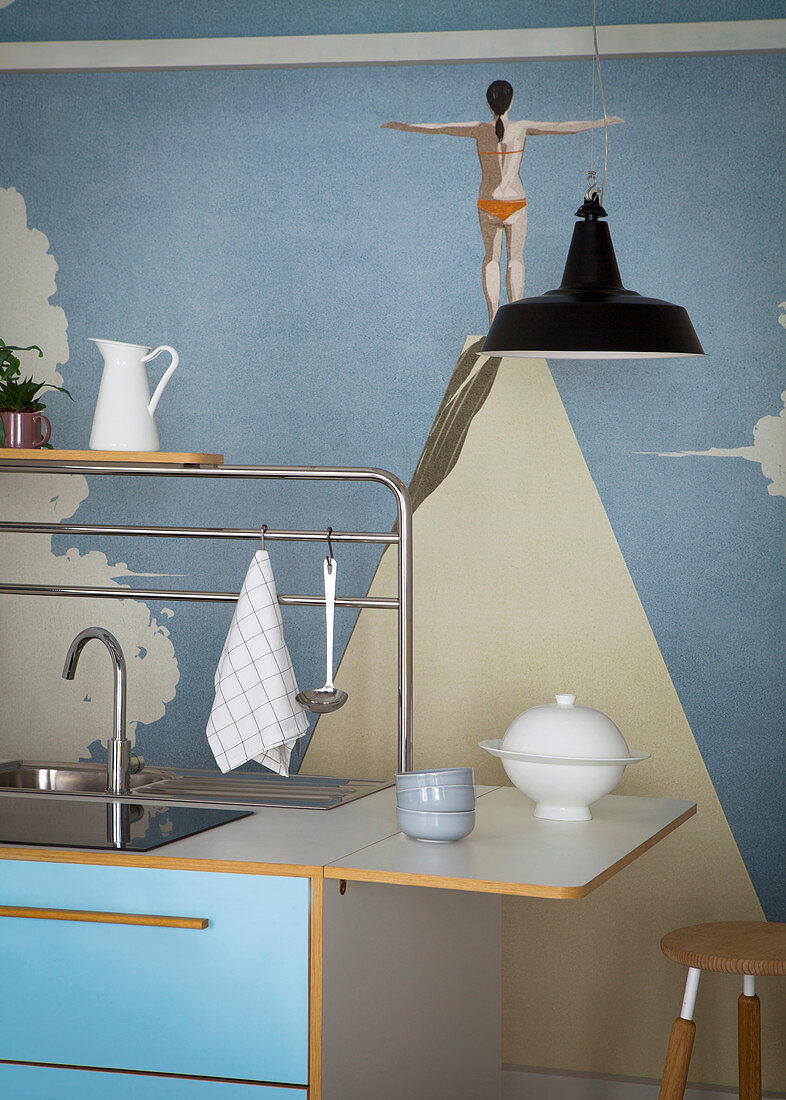 Sink unit with blue front against wall with artistic mural wallpaper