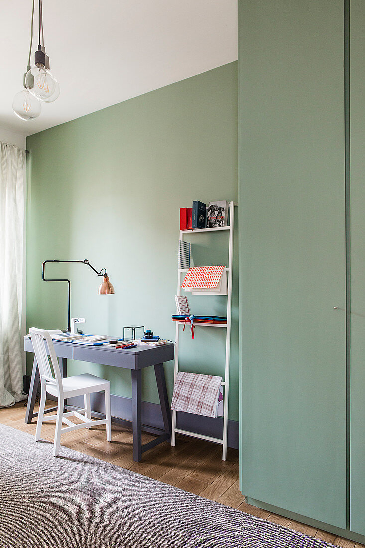 Schreibtisch und Metallleiter für Schreibutensilien in Zimmer mit mintgrünen Wänden