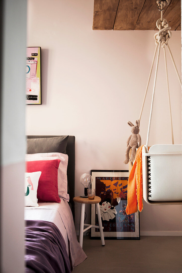 Schlafzimmer mit zartrosafarbenen Wänden und Kinderwiege an Deckenaufhängung