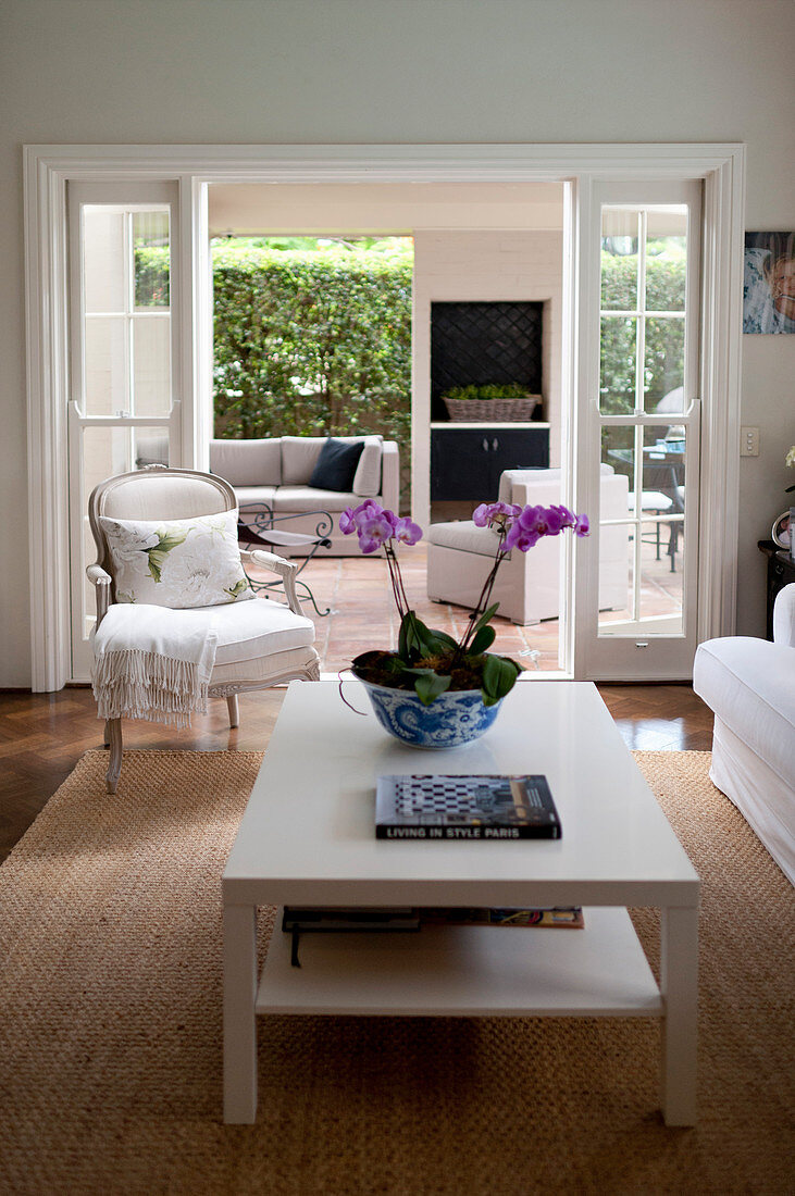 Orchid of white coffee table and armchair next to doorway leading into living room