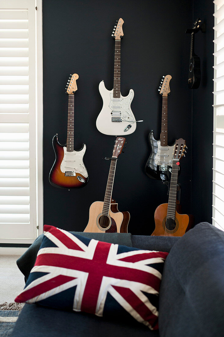 Kissen mit Union-Jack-Bezug auf Sofa, dahinter Gitarren an schwarzer Wand