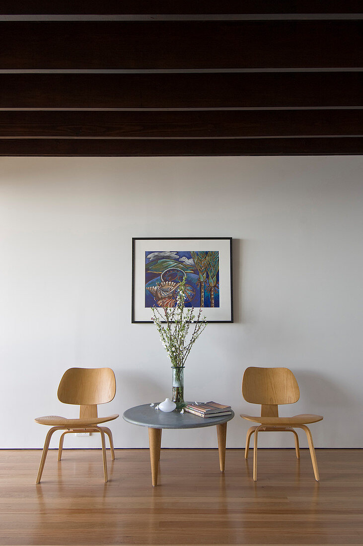 Coffeetable mit Klassikerstühlen vor weißer Wand mit Bild