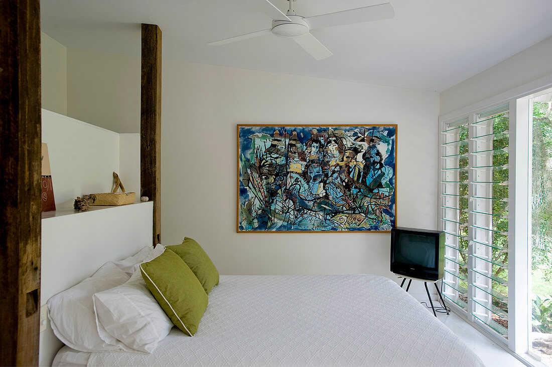 Double bed, TV and modern artwork on wall in bedroom