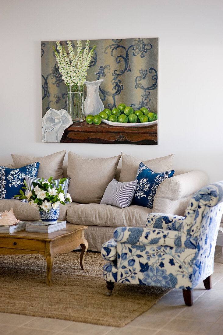 Sessel mit weiß-blauem und Sofa mit sandfarbenem Bezug im Wohnzimmer