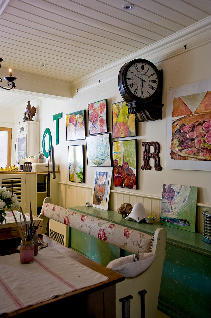 Bench, green sideboard, station clock and gallery of pictures in shabby-chic interior