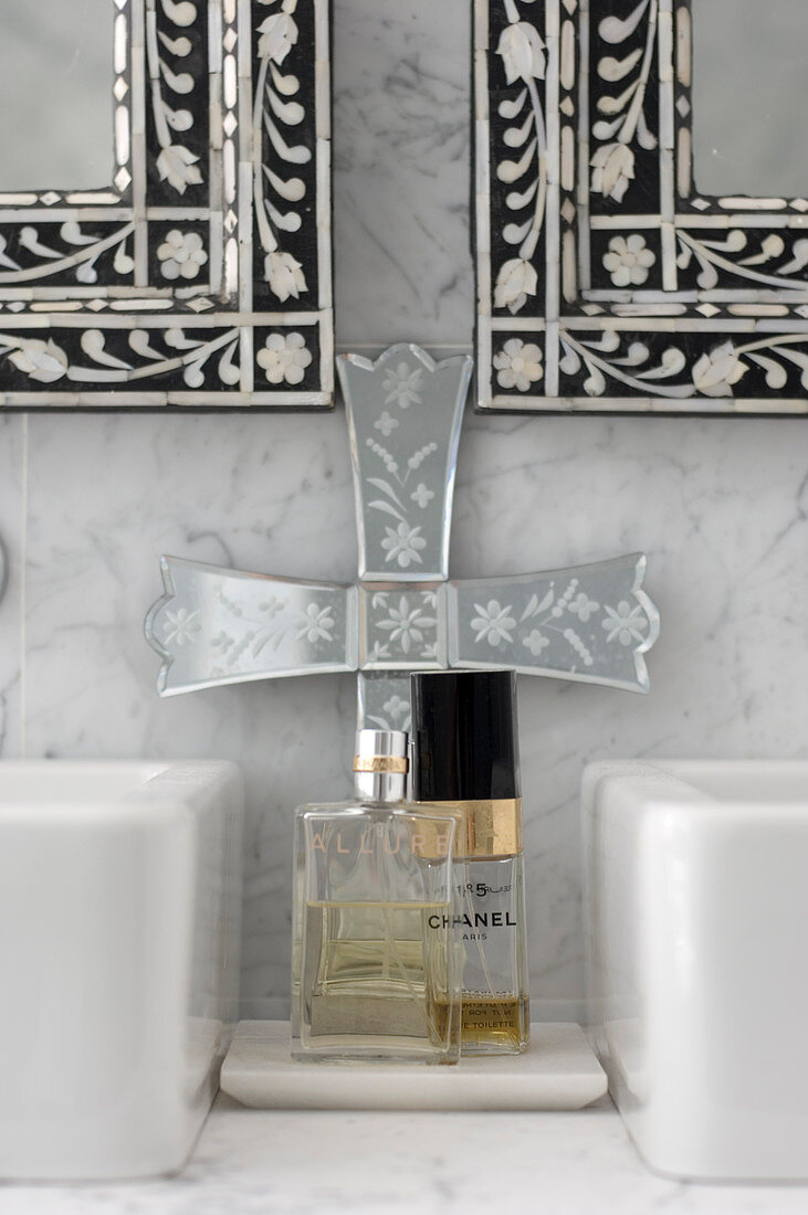 Wandspiegel mit Perlmutt-Intarsien über Marmor-Waschtisch mit Parfumfläschchen