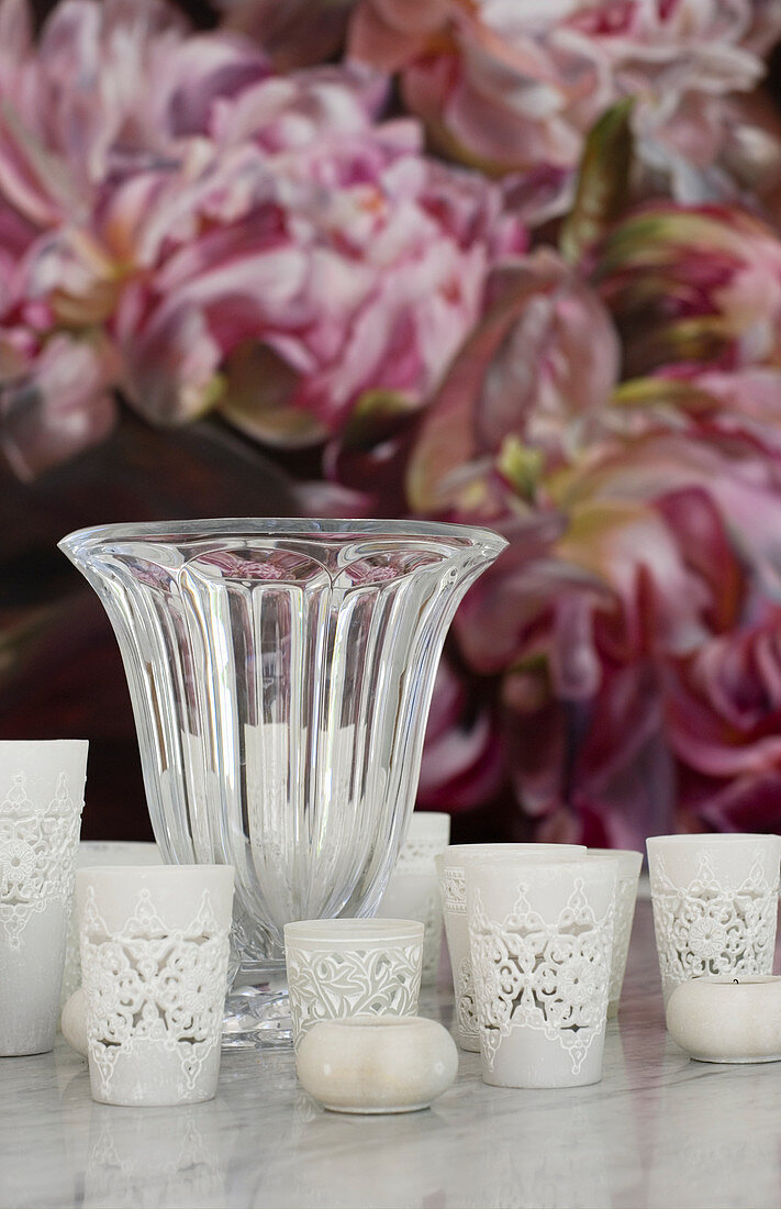 Tealight holders and vase in front of floral picture