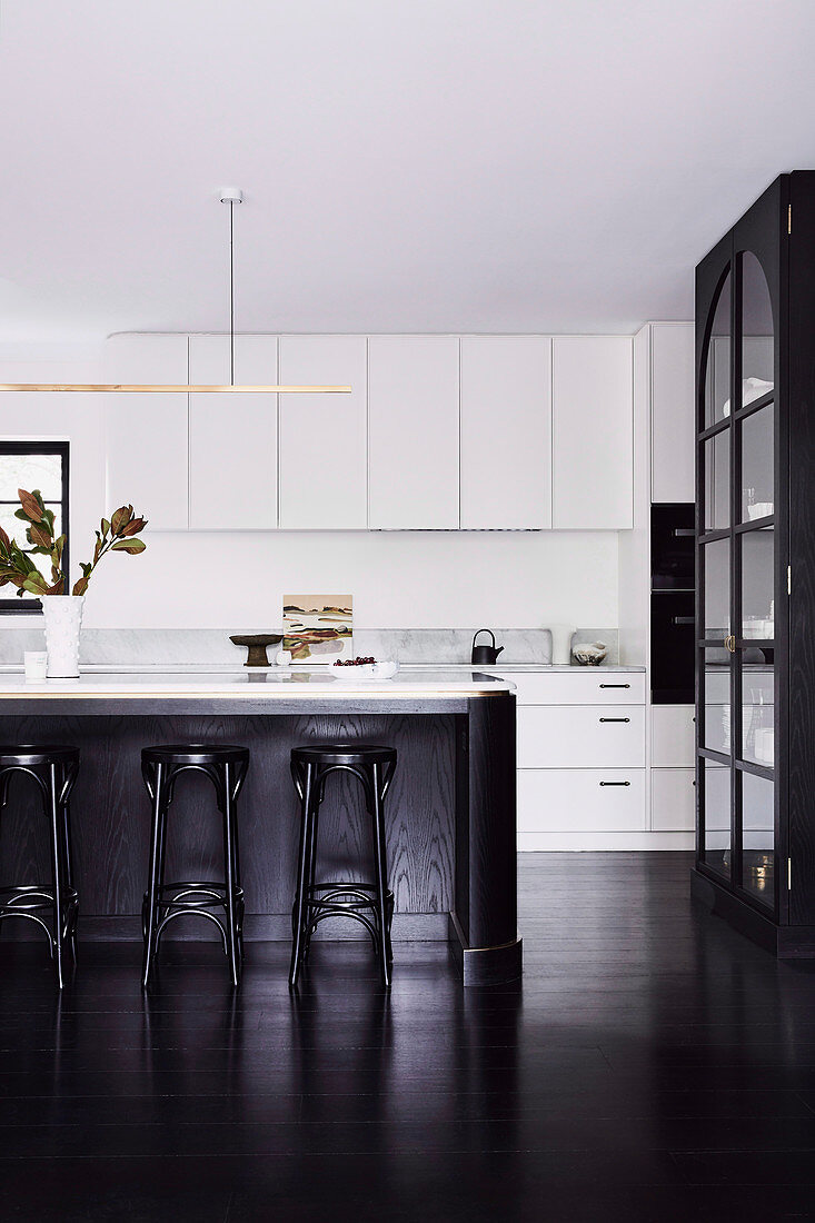 Open kitchen with white cabinets, kitchen island and dark wooden floor