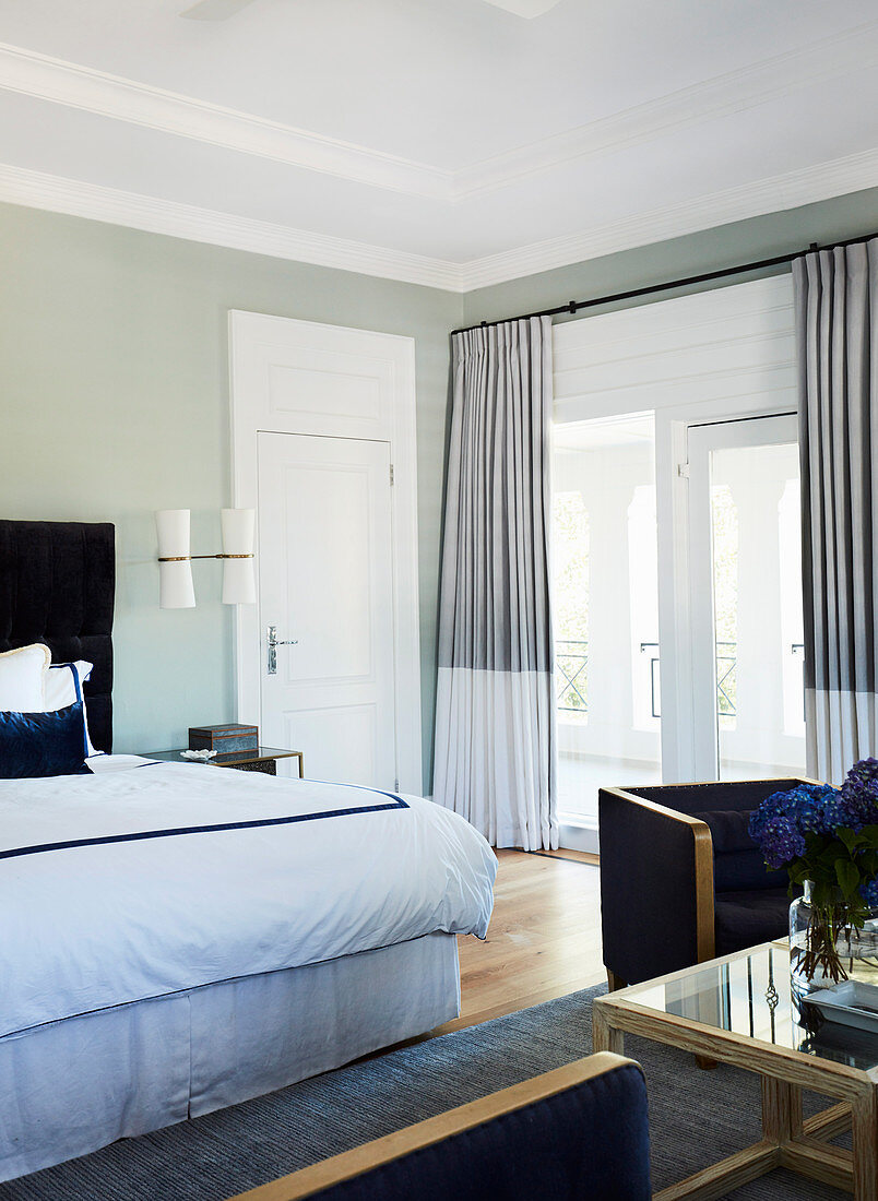 Großzügiges, elegantes Schlafzimmer mit hellgrünen Wänden
