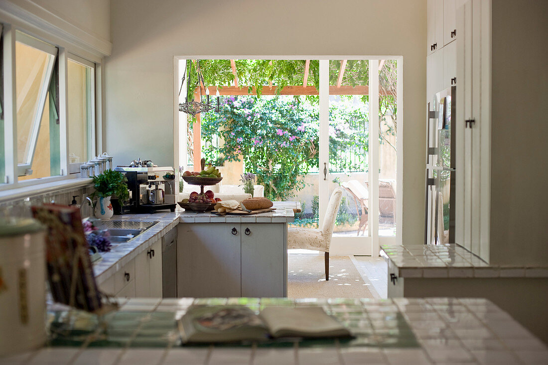 Landhausküche mit weiß gefliesten Arbeitsflächen und Zugang zur Terrasse