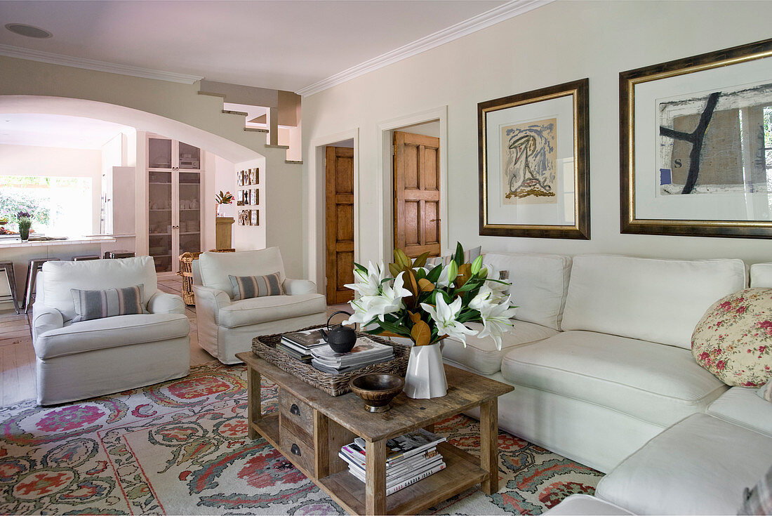 Wohnzimmer im Landhausstil mit weißem Ecksofa und Sesseln um Holz-Couchtisch